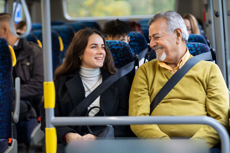En tjej och en man sitter bredvid varandra på en buss