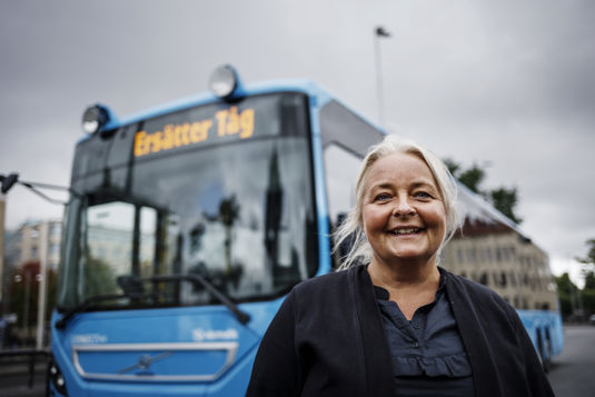 Anna-Karin står framför en ersättningsbuss och tittar in i kameran och ler.